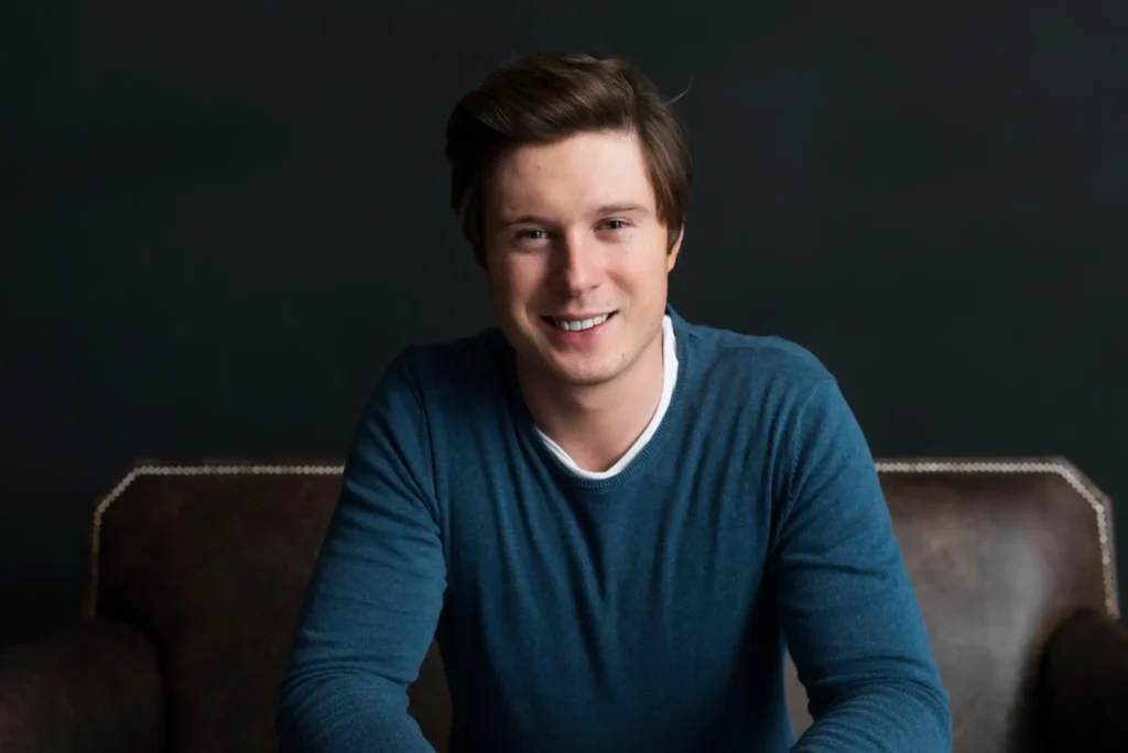 Gaming Blogger sitzt entspannt auf einem Sofa und blickt in die Kamera in moderner Umgebung