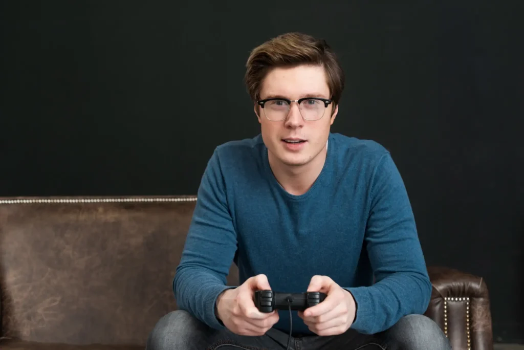 Gamer sitzt auf dem Sofa und hält einen Controller beim Videospielen in den Händen