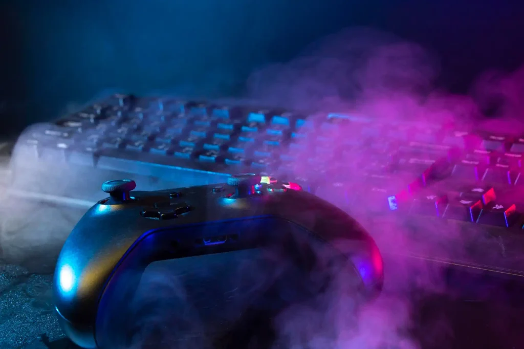 Gaming Controller vor beleuchteter Tastatur mit farbigem Licht und atmosphärischem Rauch als Gaming Setup